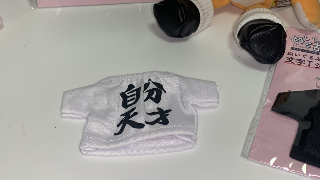 かえるのピクルスの腕を文字Tシャツの袖に通す様子
